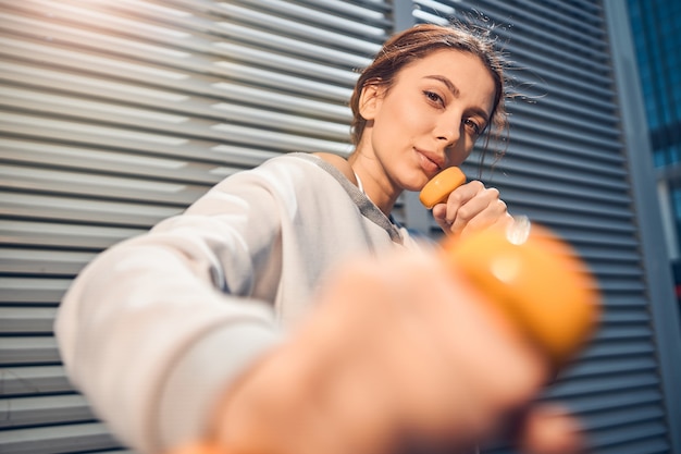 Portrait en gros plan d'une jeune sportive caucasienne professionnelle calme posant pour la caméra avec des poids