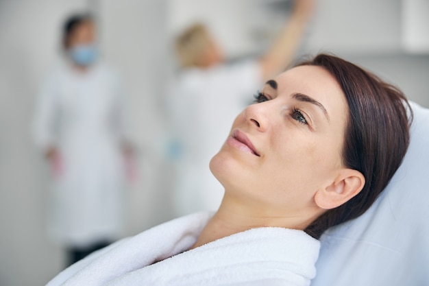 Portrait en gros plan d'une jolie femme caucasienne aux cheveux noirs d'âge moyen sereine se relaxant avant une procédure cosmétique