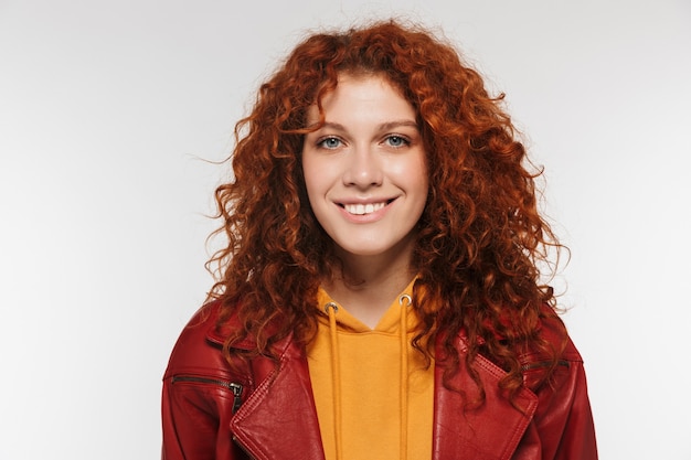 Portrait en gros plan d'une jolie femme rousse des années 20 portant une veste en cuir souriante et regardant la caméra isolée sur un mur blanc