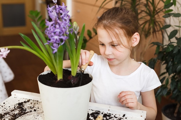 Portrait en gros plan d'une jolie fille enfant qui s'occupe de plantes d'intérieur