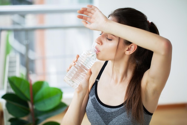 Portrait en gros plan d'une jolie jeune femme buvant de l'eau à la bouteille