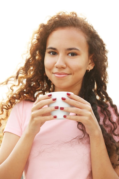 Portrait en gros plan d'une jolie jeune femme en robe rose buvant du café sur la terrasse d'été