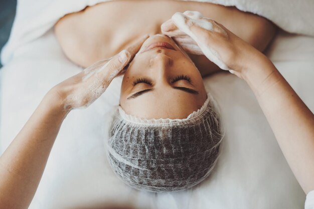 Le portrait en gros plan des mains d'esthéticiennes rend le nettoyage et l'exfoliation du visage pour le salon womanspa