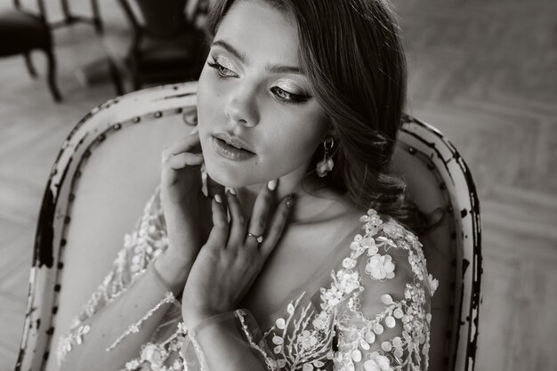 Portrait en gros plan d'une mariée luxueuse dans une robe de mariée le matin dans son intérieur. photo en noir et blanc.