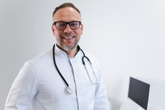 Portrait en gros plan d'un médecin de sexe masculin avec un stéthoscope autour du cou et une blouse médicale blanche