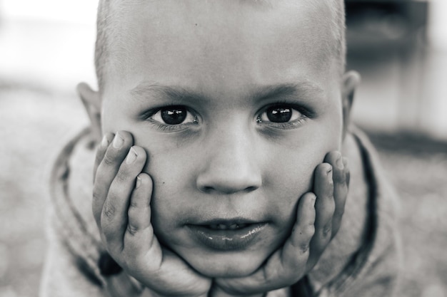 Photo portrait en gros plan d'un mignon garçon avec les mains sur le menton