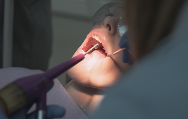 Portrait en gros plan d'une patiente chez le dentiste de la clinique belle fille en fauteuil dentaire sur le