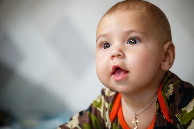 Portrait en gros plan d'un petit garçon âgé de 8 mois et souriant. Habillé en costume militaire