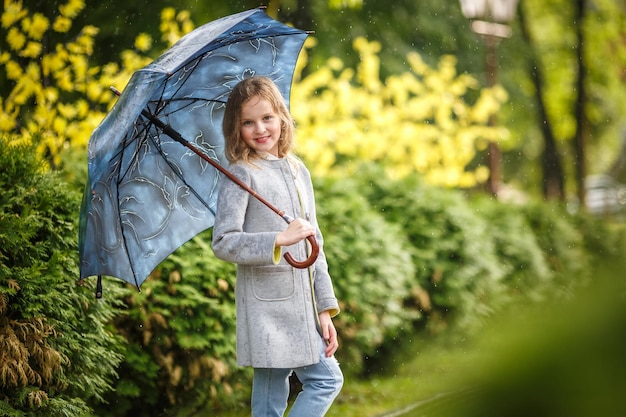 Portrait en gros plan d'une petite belle fille élégante avec un parapluie sous la pluie dans le parc