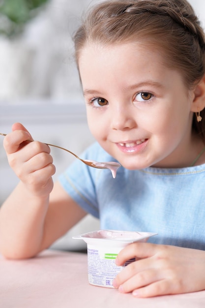 Portrait en gros plan d'une petite fille mignonne mangeant un délicieux yaourt