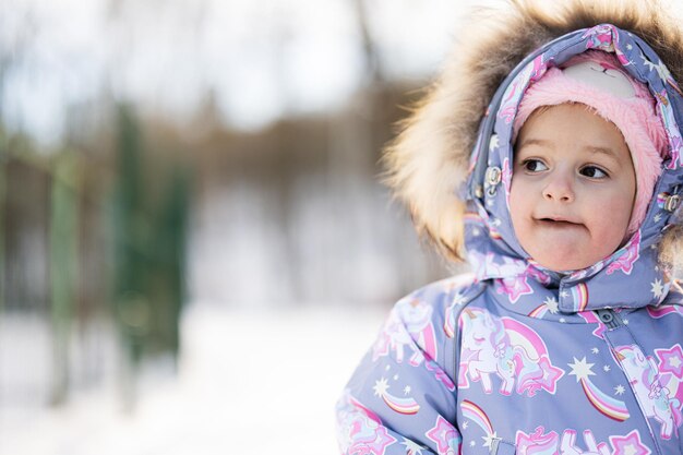 Portrait en gros plan d'une petite fille portant un habit de neige pour enfant lors d'une journée d'hiver glaciale et ensoleillée