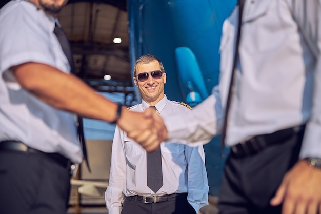 Portrait en gros plan d'un pilote de race blanche adulte en chemise blanche, debout derrière la poignée de main des hommes à l'extérieur