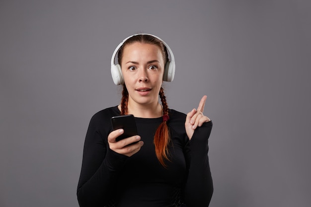 Portrait en gros plan d'un podcast féminin caucasien ou d'une écoute de musique sur fond gris. écouter de la musique au casque