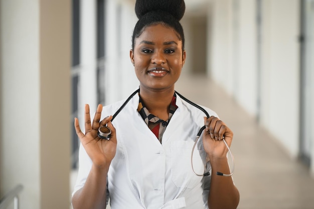 Portrait en gros plan d'une professionnelle de la santé féminine confiante et souriante avec blouse de laboratoire, stéthoscope. Fond de clinique d'hôpital isolé. Le temps d'une visite au bureau