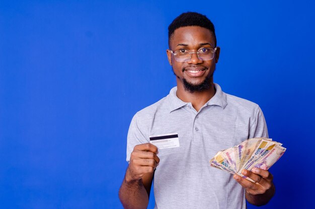 Portrait en gros plan de son beau mec joyeux et attrayant, heureux et joyeux, tenant dans les mains une nouvelle carte bancaire en espèces du ventilateur