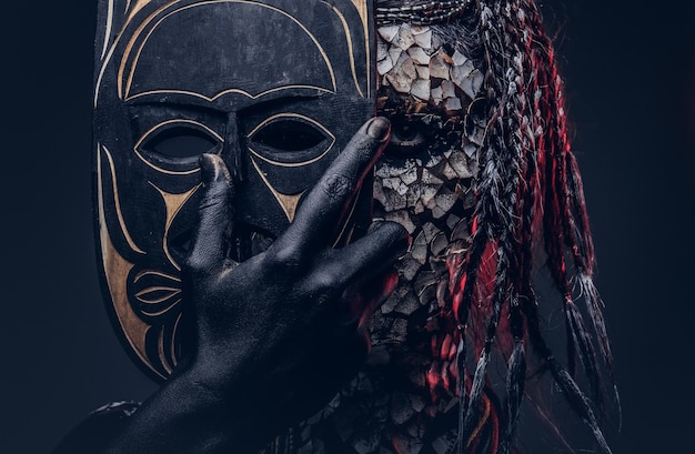 Photo portrait en gros plan d'une sorcière de la tribu africaine indigène, vêtue d'un costume traditionnel. notion de maquillage. isolé sur un fond sombre.