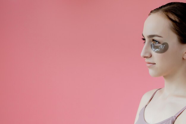 portrait gros plan souriant jeune femme avec masque de patchs hydratants sous les yeux, procédure de soin de la peau.