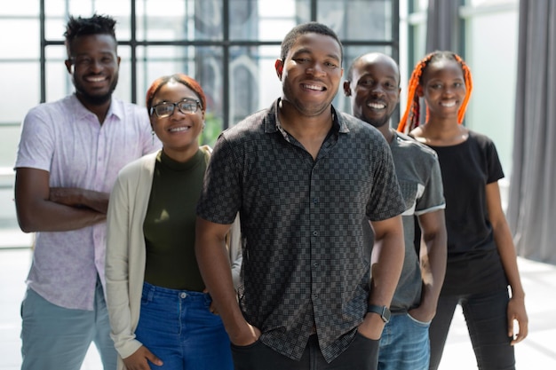 Portrait de groupe de cinq collègues de travail africains debout dans une rangée au bureau