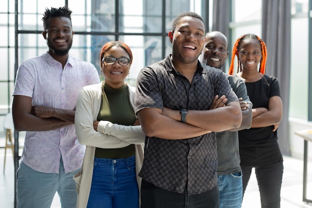 Portrait de groupe de cinq collègues de travail africains debout dans une rangée au bureau