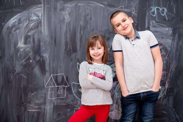 portrait de groupe d'enfants heureux garçon et petite fille debout devant un tableau noir