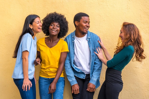 Portrait de groupe de jeunes amis multiethniques contre le mur jaune communauté internationale de jeunes