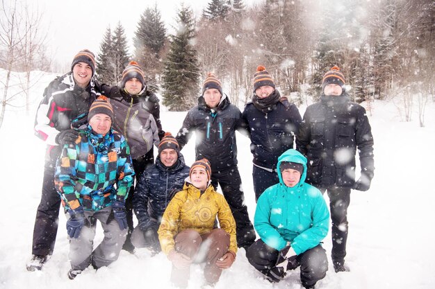 portrait de groupe de jeunes gens d'affaires heureux profitant d'une journée d'hiver enneigée avec des flocons de neige autour d'eux lors d'un team building dans la forêt de montagne