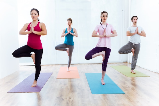 Portrait d'un groupe de personnes pratiquant le yoga à la maison. Pose de Vrksasana.