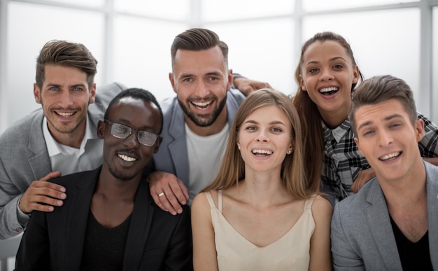 Portrait d'un groupe souriant de divers collègues d'entreprise debout ensemble à une table dans un bureau moderne et lumineux