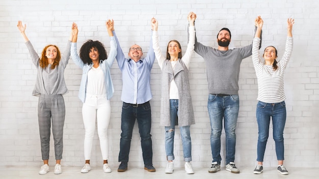 Portrait de groupe de team building de personnes heureuses se tenant par la main et levant la main ensemble