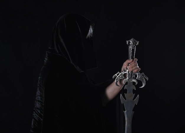 portrait d'un guerrier médiéval dans une hotte avec une épée sur fond noir