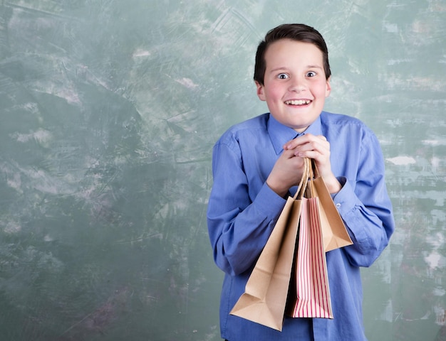 Portrait happy smiling boy adolescent avec des sacs à provisions sur fond vert