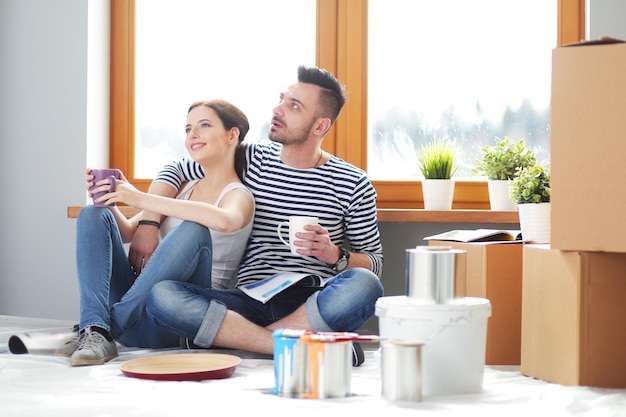 Portrait happy smiling young couple painting mur intérieur de nouvelle maison jeune couple