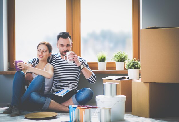 Portrait happy smiling young couple painting mur intérieur de nouvelle maison jeune couple