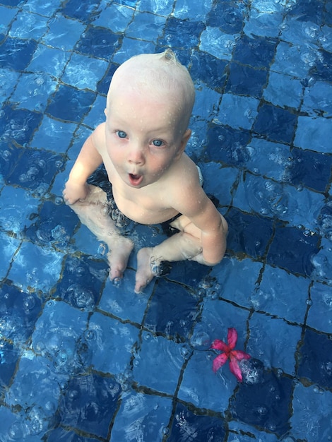 Photo portrait en haut angle d'un bébé assis dans une piscine