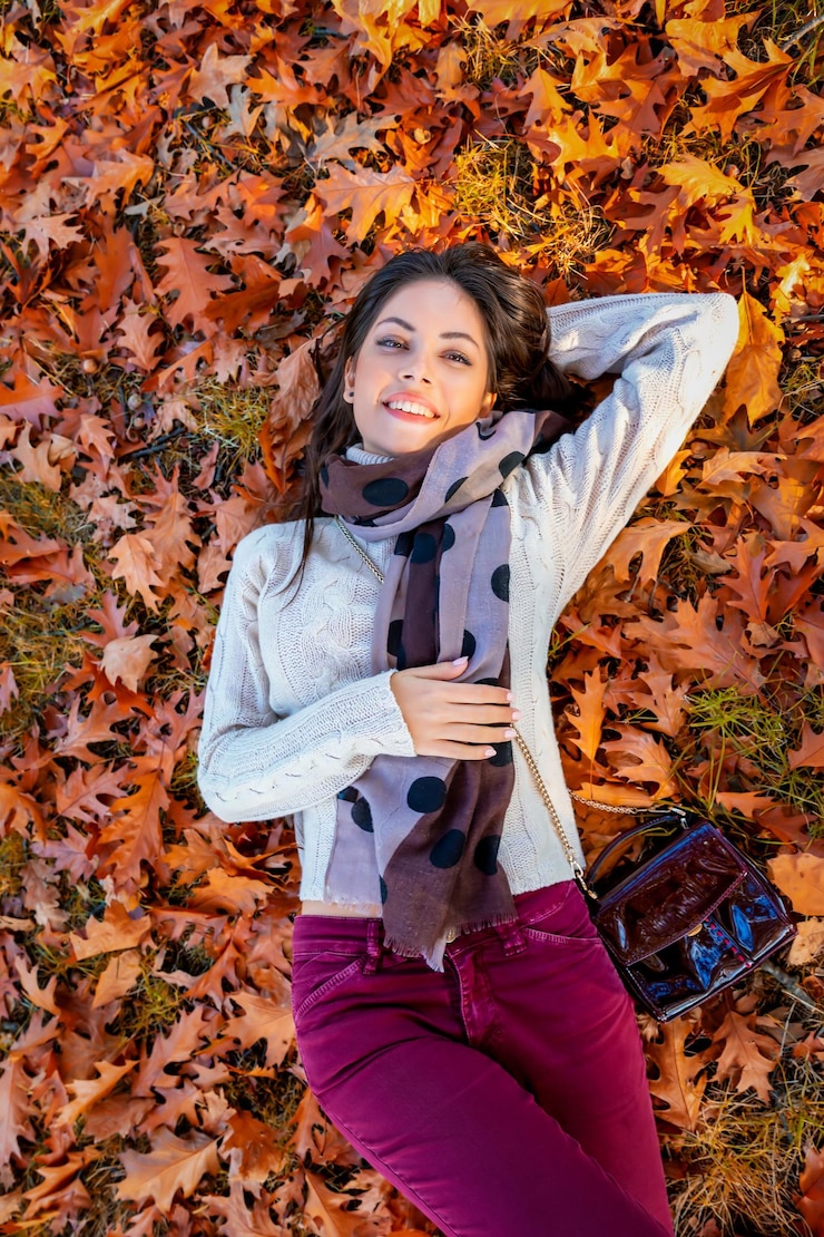 Photo portrait en haut angle d'une jeune femme souriante allongée sur des feuilles d'automne
