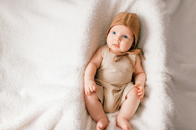 Portrait d'en haut de joli petit bébé en pyjama élégant allongé sur le lit