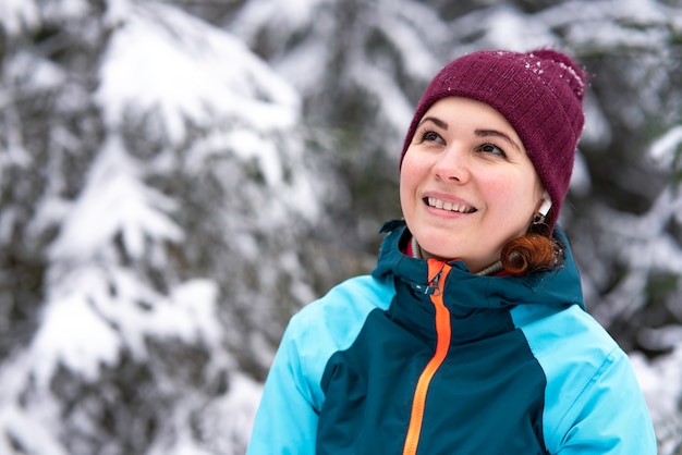 Portrait de l'heureuse belle jeune femme souriante dans une forêt enneigée d'hiver