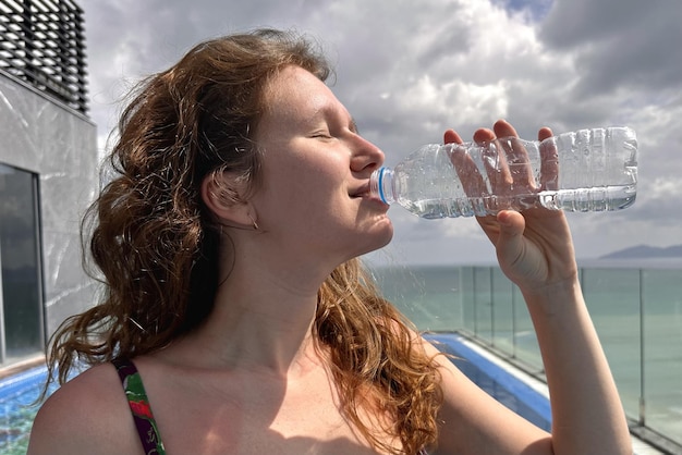 Portrait d'heureuse fille assoiffée positive jeune belle femme boit de l'eau minérale fraîche pure