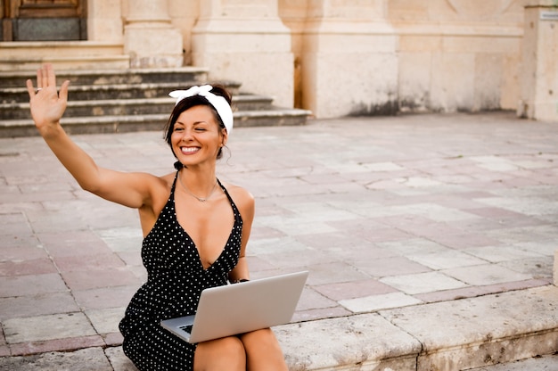 Portrait de heureuse jeune femme assise sur les marches d&#39;un bâtiment à l&#39;aide d&#39;un ordinateur portable