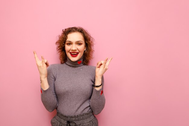 Portrait de l'heureuse jolie dame en pull gris et cheveux bouclés