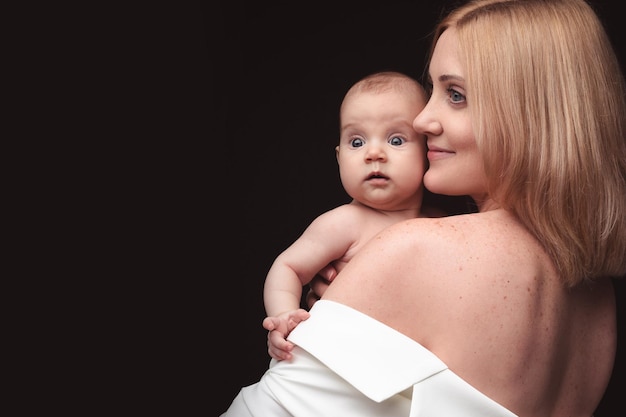 Portrait d'heureuse mère et bébé sur fond noir