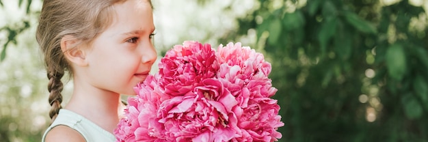 portrait d'une heureuse petite fille caucasienne de sept ans, tient dans les mains et sent et profite