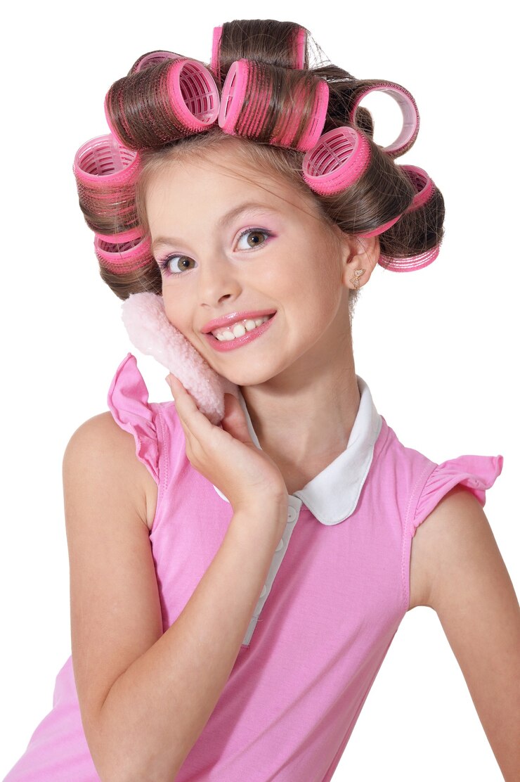 Photo portrait d'heureuse petite jolie fille en bigoudis en studio