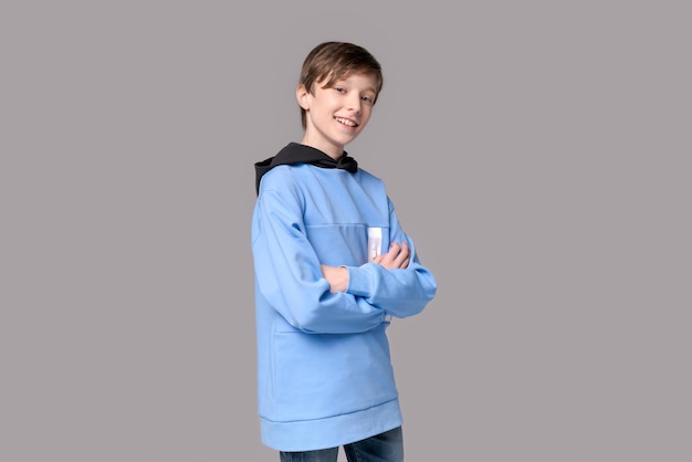 Portrait heureux adolescent caucasien homme en sweat-shirt bleu sur la couleur grise