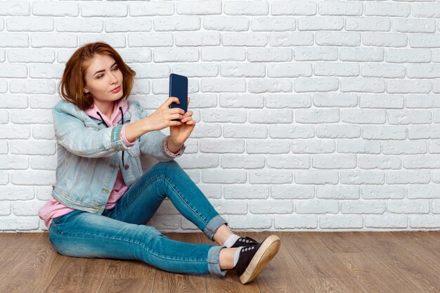 Portrait, heureux, désinvolte, femme, séance, plancher, utilisation, smartphone