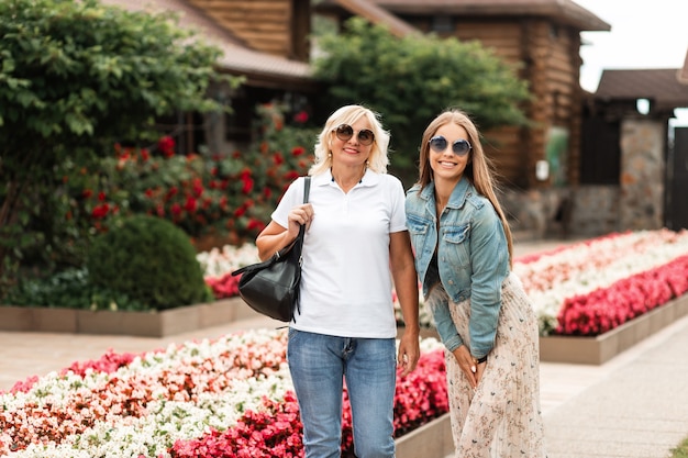 Portrait heureux de deux belles femmes heureuse maman âgée et fille joyeuse à lunettes de soleil dans des vêtements de jeans à la mode à l'extérieur le week-end en famille