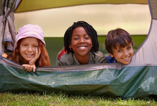 Photo portrait heureux et enfants dans la tente pour le campement en vacances aventure ou vacances avec plaisir voyage de sourire et jeunes enfants se liant ensemble dans la forêt de champ en plein air ou les bois en voyage de week-end d'été