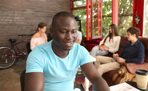 Portrait d'un heureux entrepreneur afro-américain affichant un ordinateur au bureau