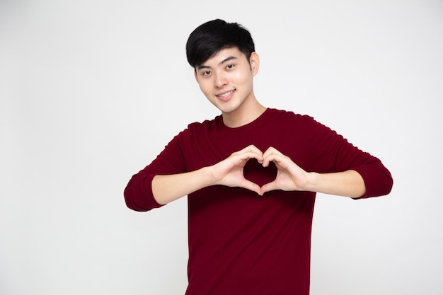 Portrait d'heureux homme asiatique faisant coeur avec les doigts isolés sur fond blanc
