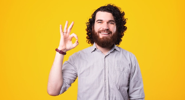 Portrait d'heureux homme gai aux cheveux bouclés montrant le geste ok